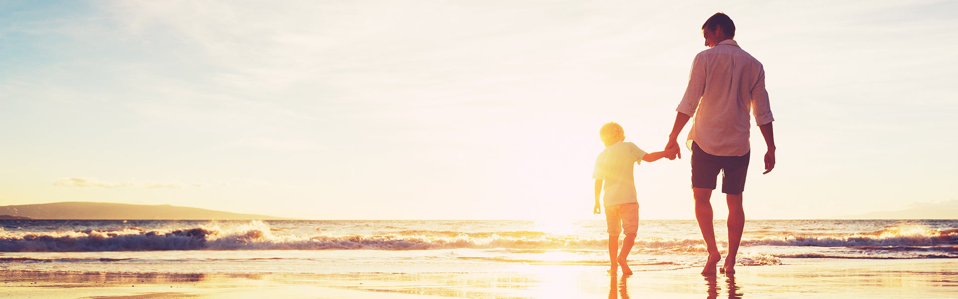 boy and father walking towards the sea